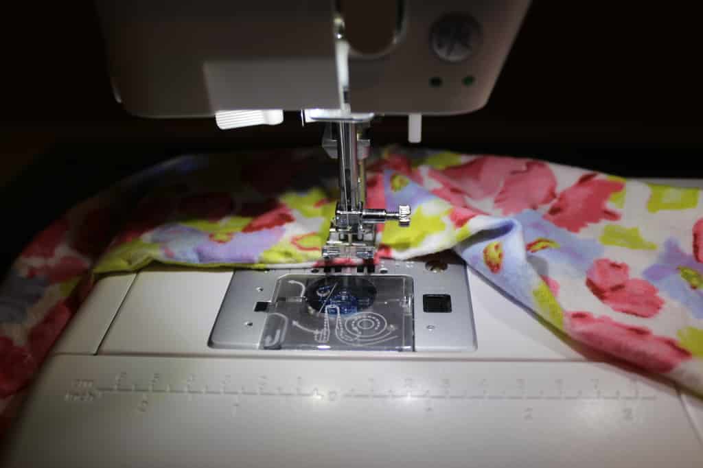 Flowered material being sewed with sewing machine.