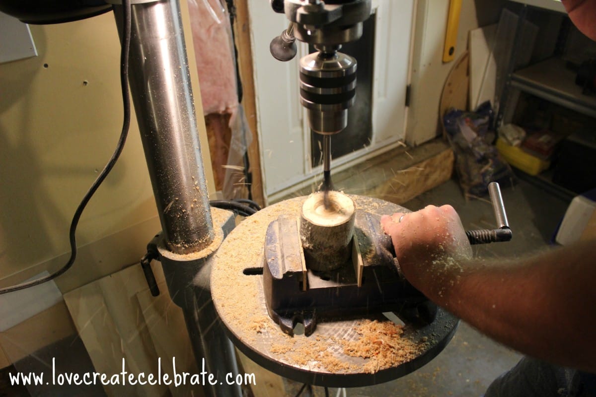 Use a drill press to cut halfway through the top of each log of the wooden candle holders