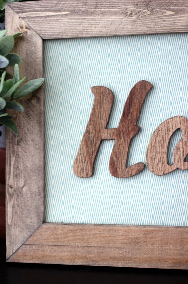 Attach the letters and frame to the wooden board with wood glue and a staple gun