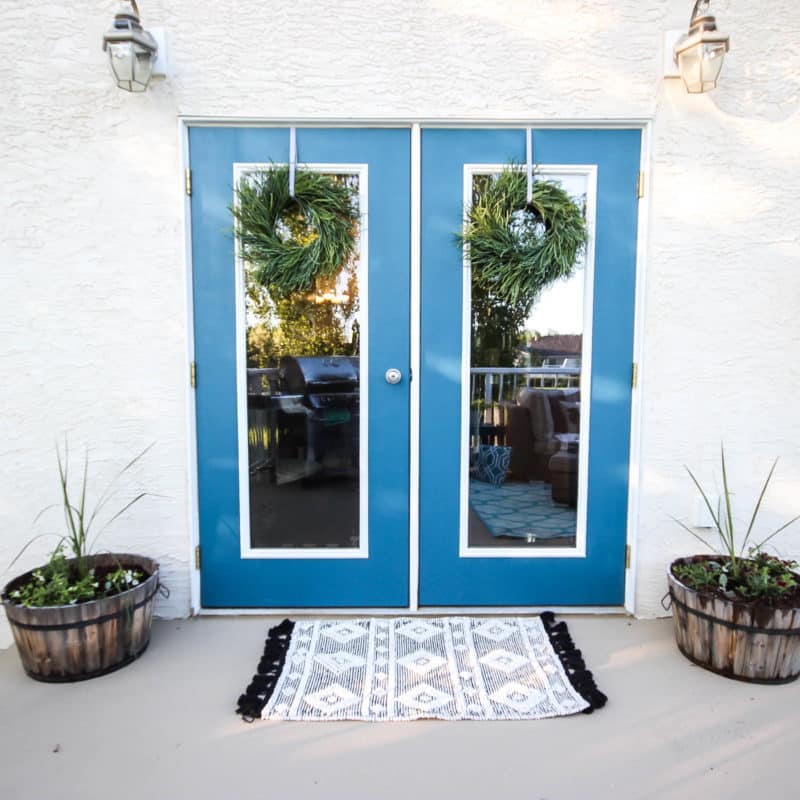 A stunning backyard makeover inspired completed with Behr paints. Love the bright painted blue doors, and the grey outdoor sectional. Beautiful DIY pallet side tables, and black and white accessories complete the space. Summer is here!