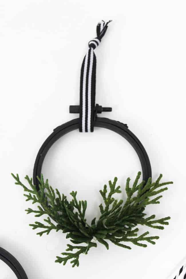 Use hot glue to attach the juniper leaves to the hoop and tie a strand of ribbon around the top
