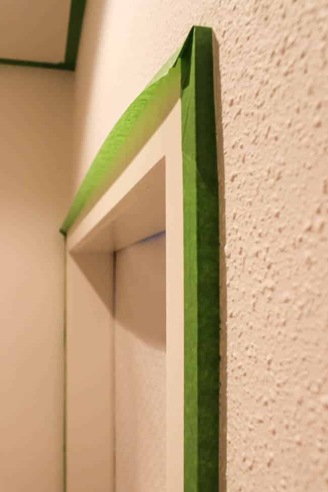 Painter's tape blocking a door frame for prep painting textured walls