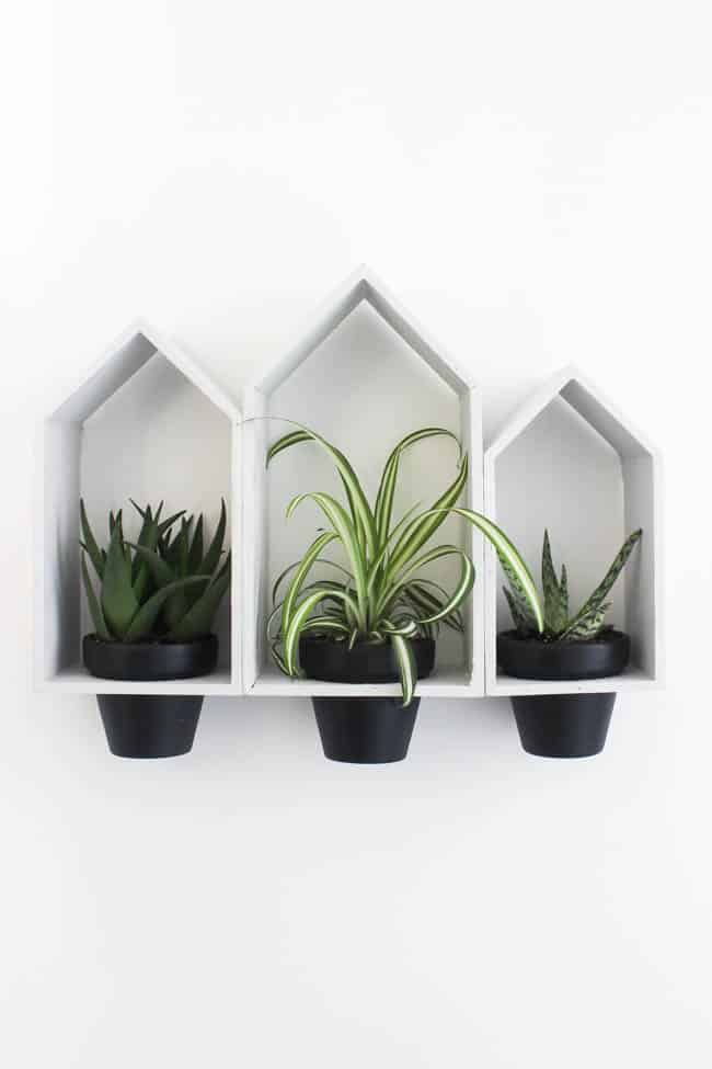 Beautiful Hanging Wall Planters to bring some greenery into your home! Love the modern look of these planters, and the dollar store price tag! Buy the terra cotta pots and wooden houses from the dollar store!