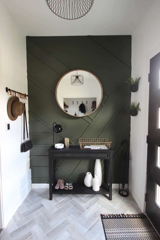 This gorgeous modern entryway reveal is here! What a huge transformation from the outdated space it once was! From the beautiful bench, to the herringbone floors, to the black front door, and the wood accent feature wall. This entry is stunning!