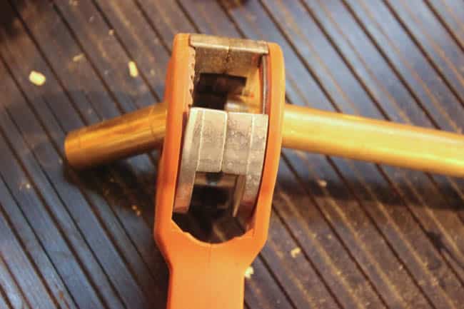 Cutting copper pipe with a ratcheting tool for the DIY copper pipe fall wreath.