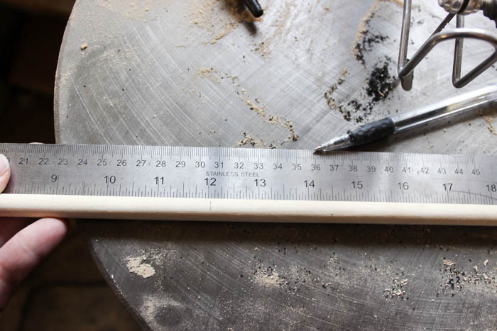 Measuring the dowel so you can cut your custom pieces for the modern boho fall wreath.