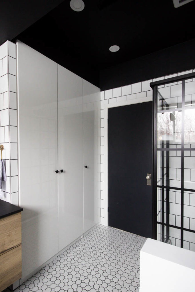 Wow! This modern Bathroom Reveal is absolutely stunning! What a gorgeous space! Everything from the black tub and shower frame, the champagne bronze faucets, and the wood vanity to the black ceiling and built-in storage units! What an incredible transformation! #modernbathroom #paintedceiling #blackceiling #blackandwhite #bathroom #remodel #renovations