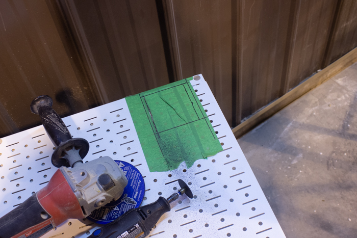 preparing to cut into metal pegboard for outlet installation