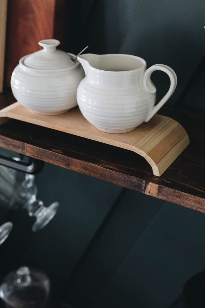 close up of white sugar and creamer set sitting on modern wooden pedestal made from a dollar store shelf