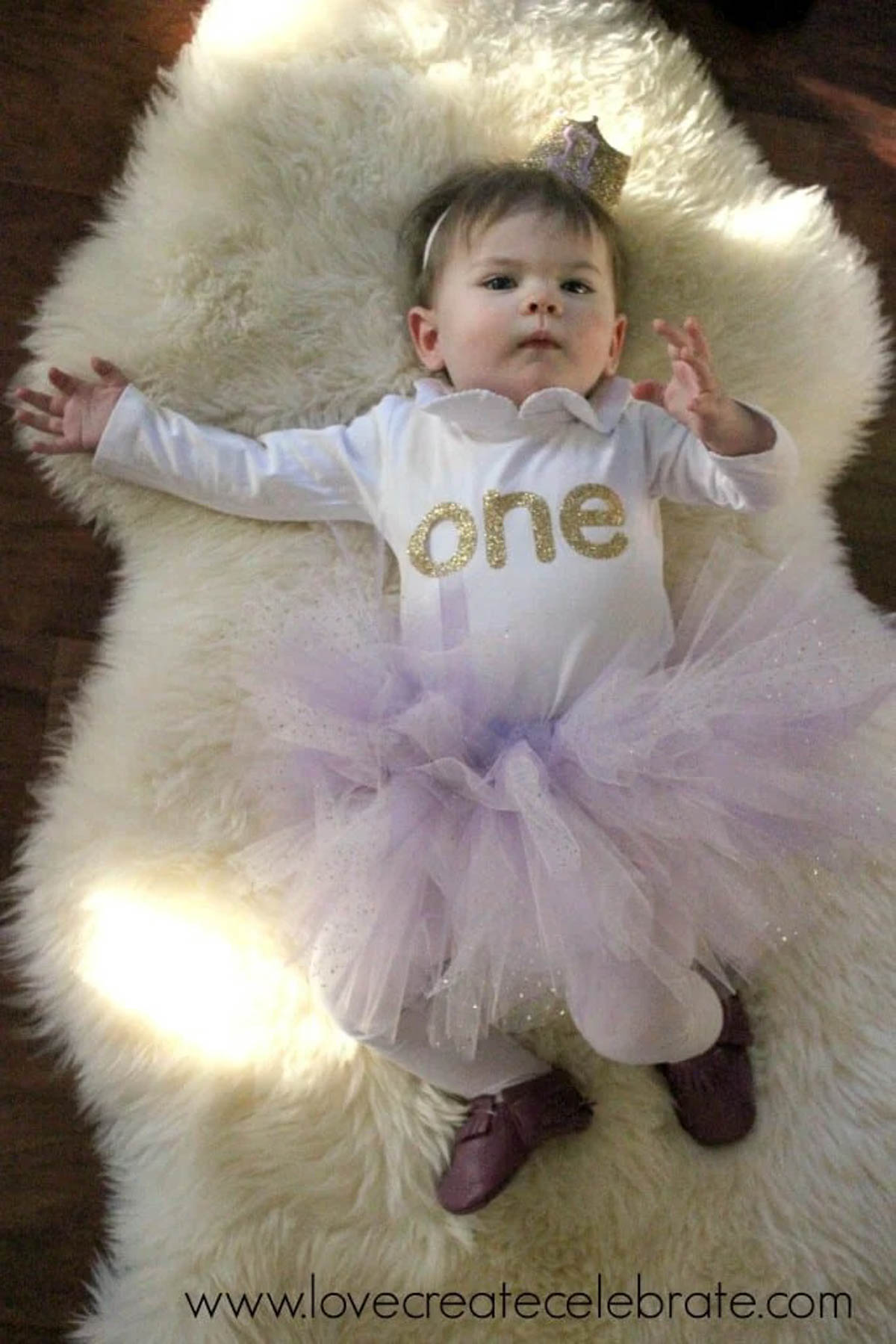 Baby in first birthday onesie, crown, and tutu