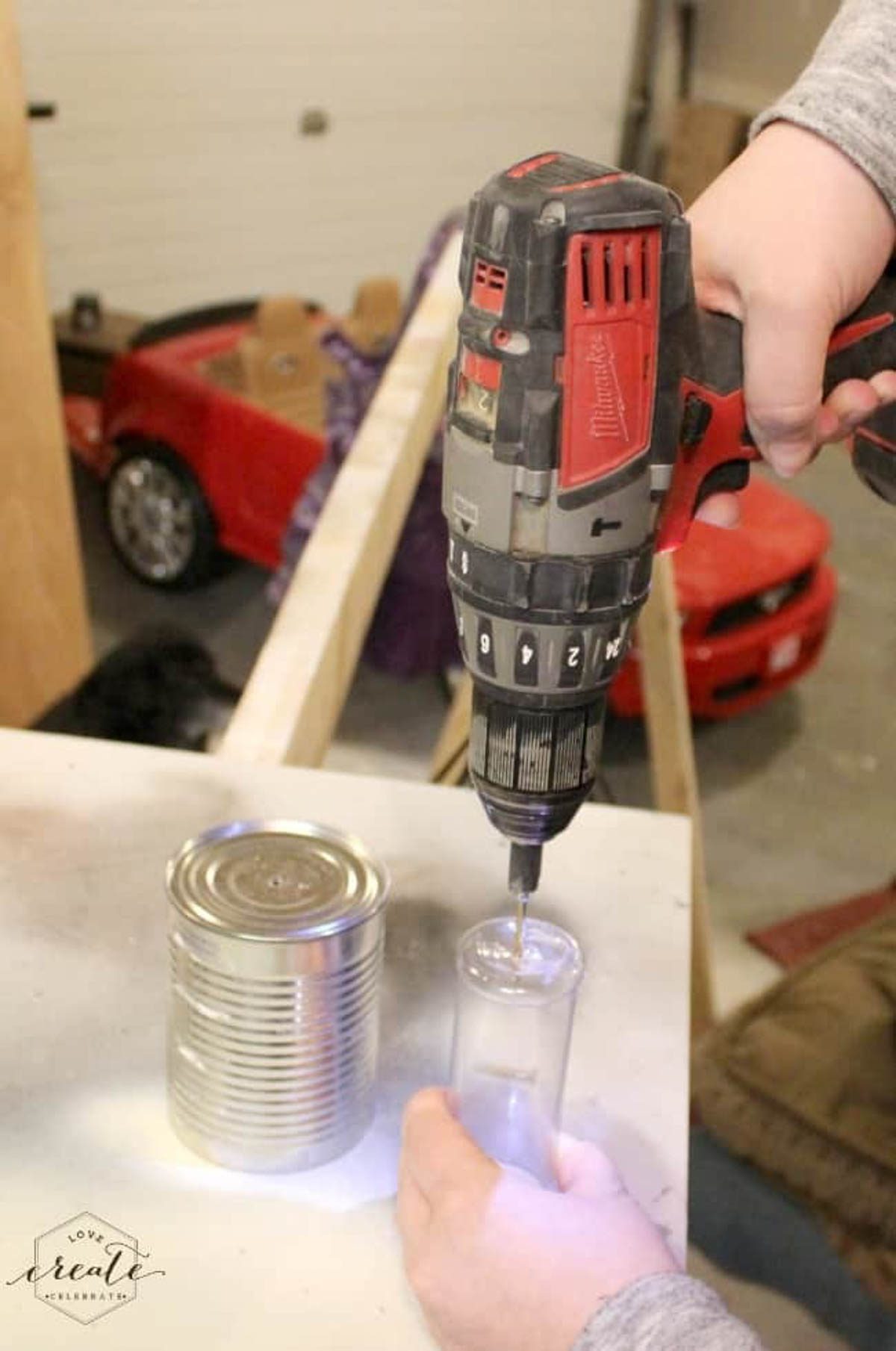 Drilling a hole into a plastic cylinder to sit inside the tin can for the concrete vase