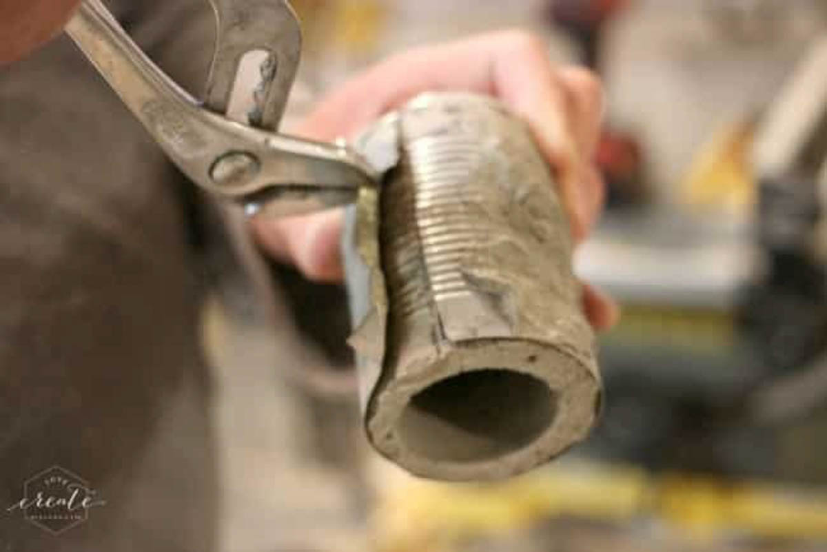 Use pliers to remove tin can from concrete vase