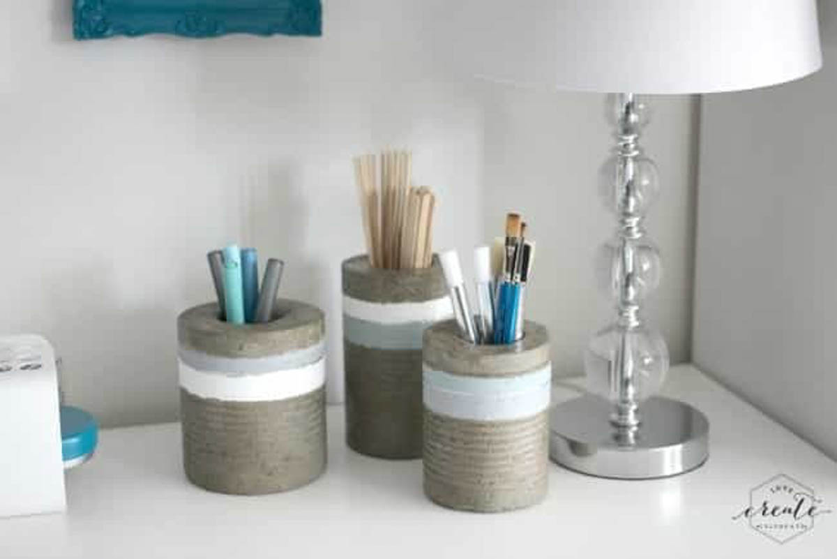 Three concrete vases holding art supplies created using a tin can