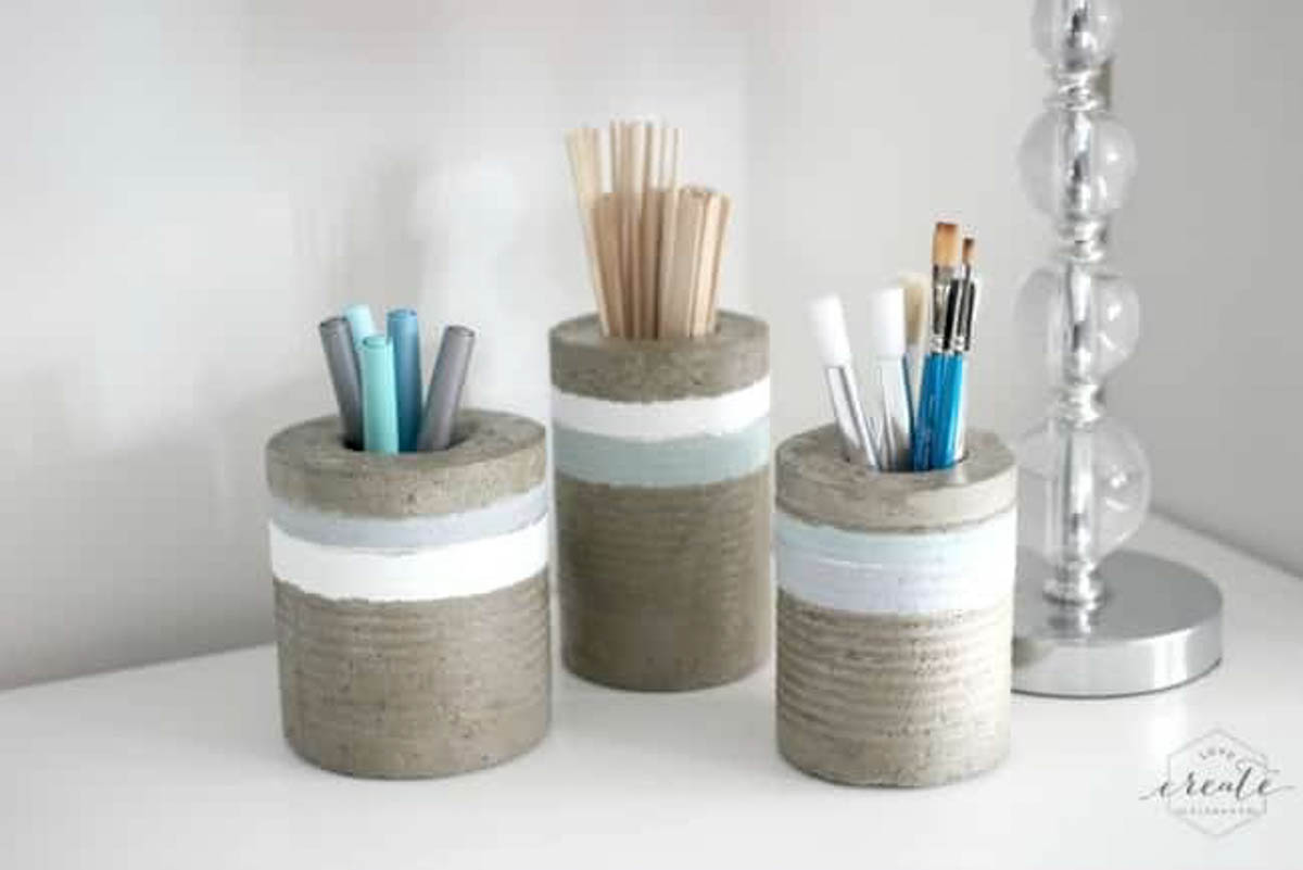 Three concrete vases painted and filled with art supplies