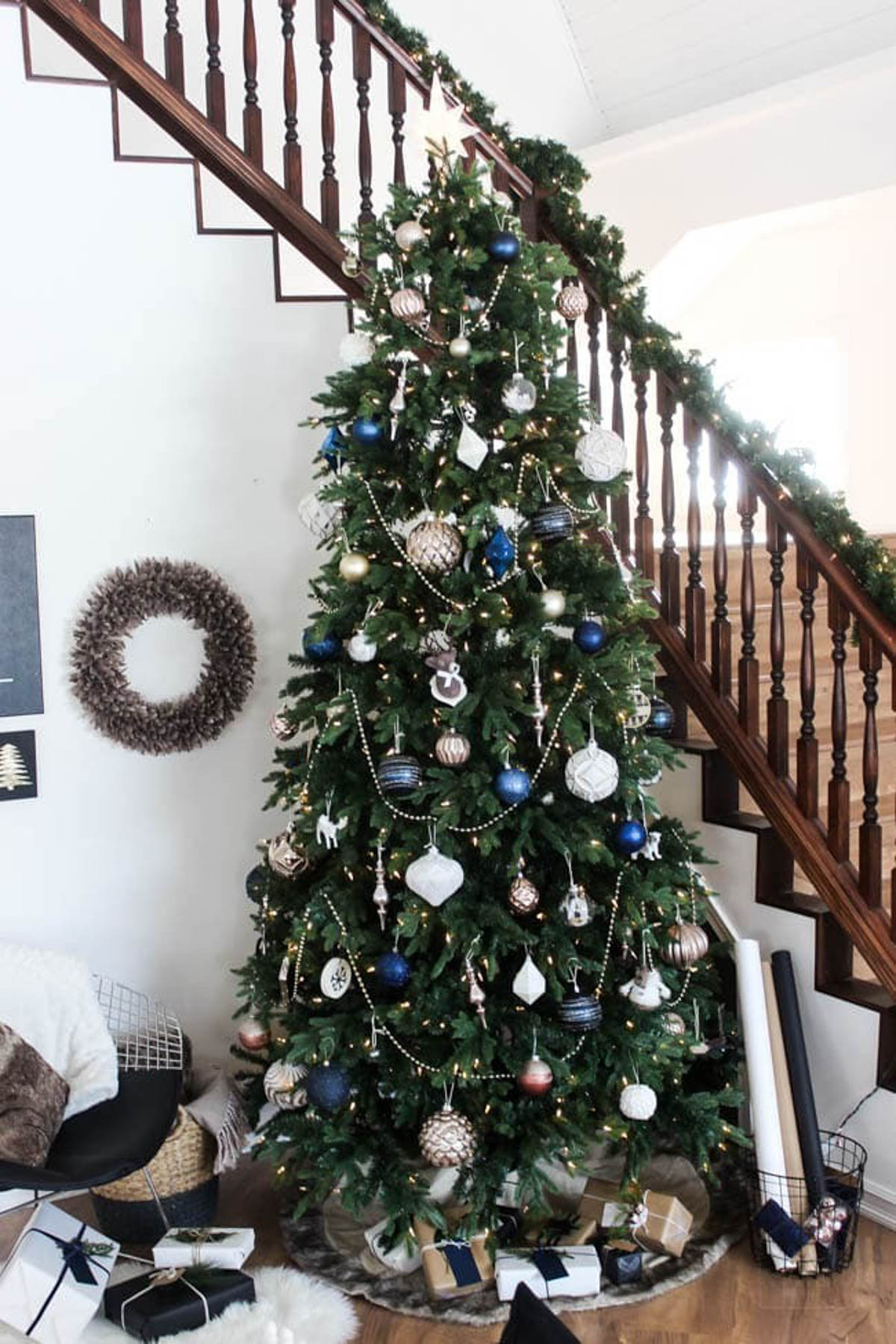 Decorated designer Christmas tree by a stairway.
