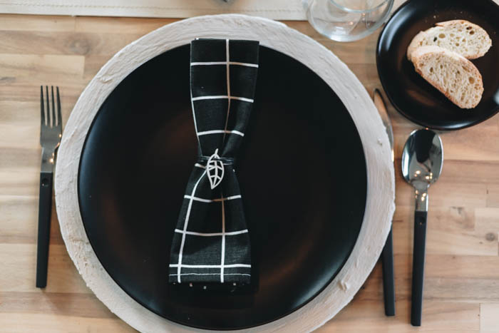 place setting with charger, black plate, and napkin with minimalist napkin ring