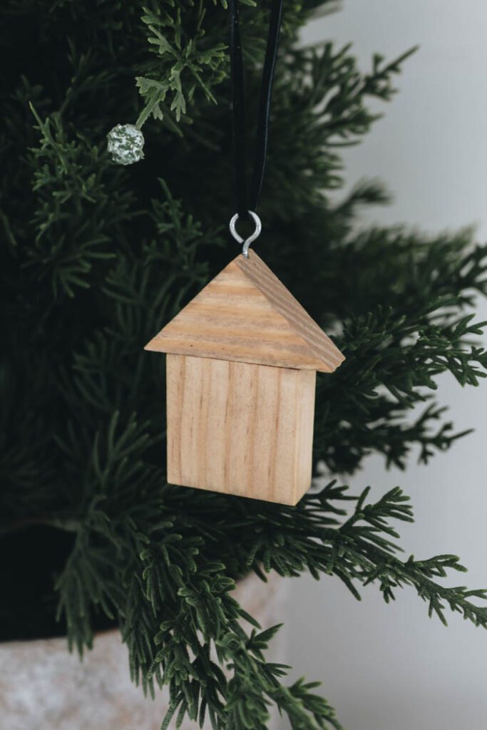 close up image of wooden house ornament hanging on a Christmas tree