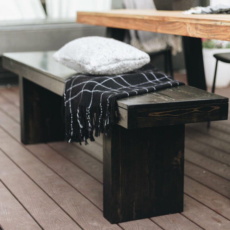 Outdoor bench beside teak table with black legs