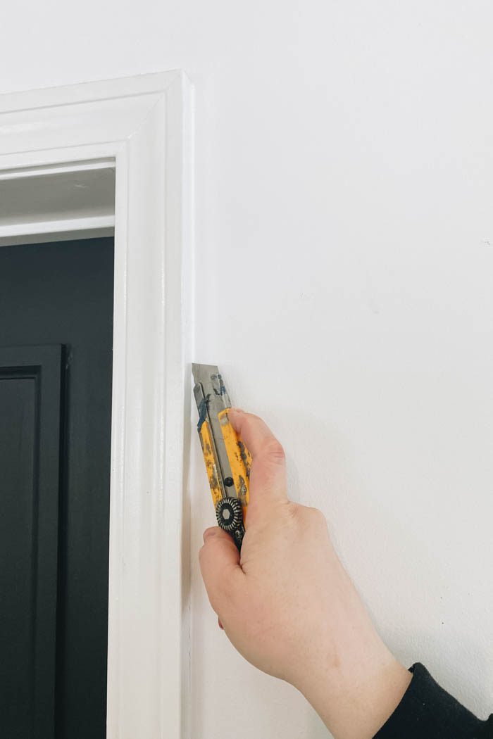 using a utility knife to score edge between moulding and wall